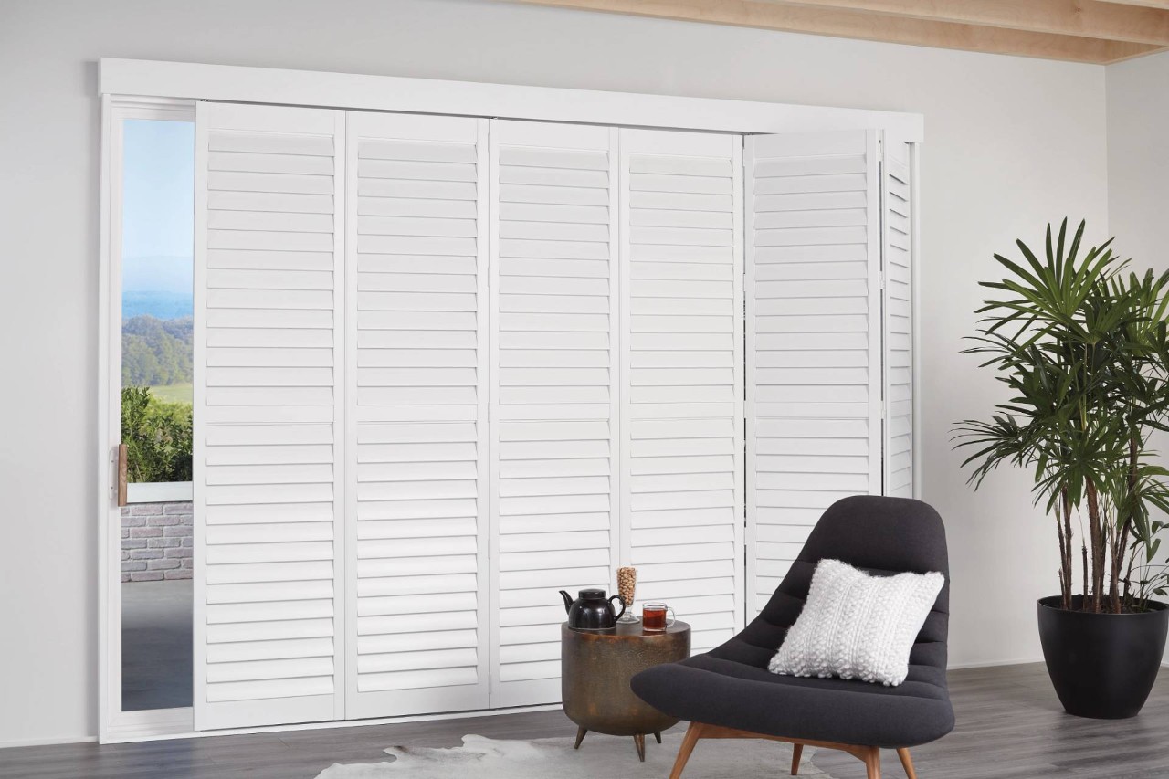 Neutral-colored room with white Hunter Douglas Newstyle® Hybrid Sliding Shutters installed on a wide window near Campbell, CA
