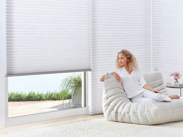 Living room with windows featuring Duette® Honeycomb Shades with PowerView® Automation.